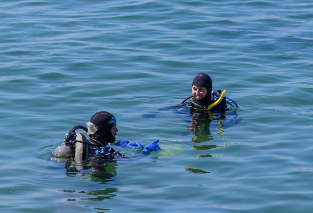 pexels photo 16851074 Two scuba divers enjoying a sunny day in clear open water, equipped with full scuba gear.