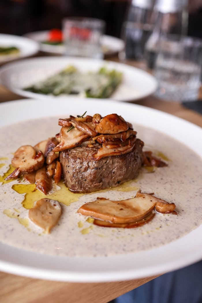 services-img Delicious fillet steak served with wild mushrooms and creamy sauce on a plate in a restaurant.